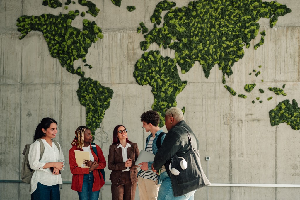 People standing in front of a green moss world map on a concrete wall