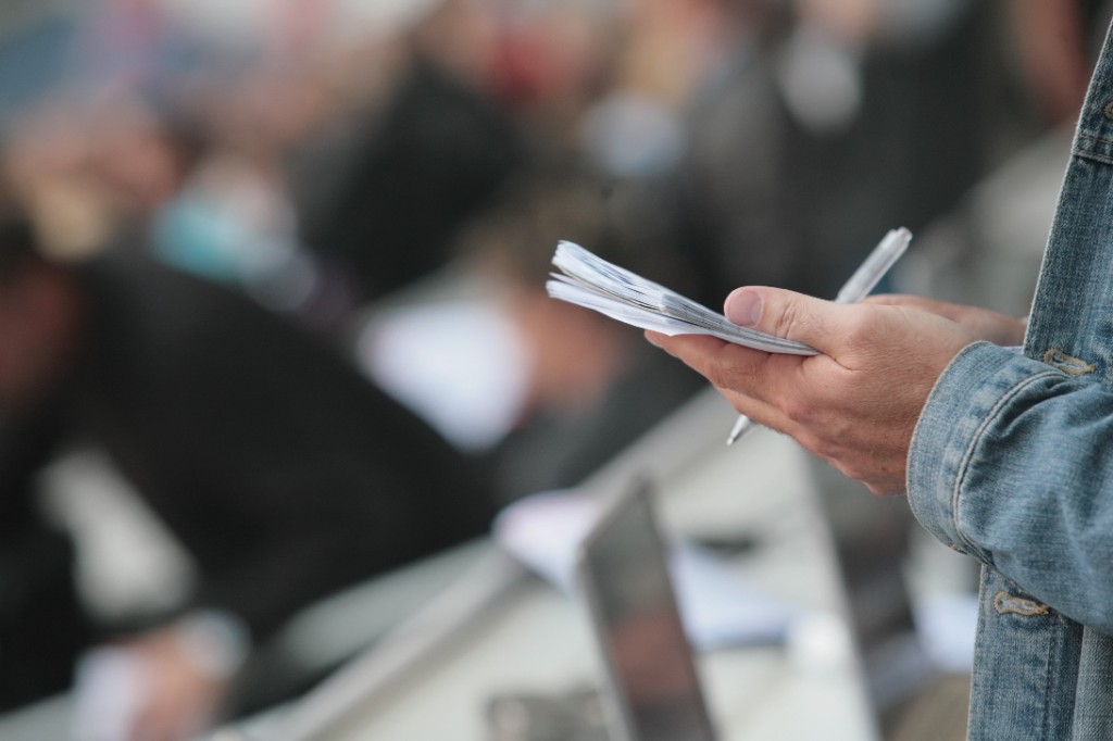 Hands holding a notepad and pen, ready to take notes